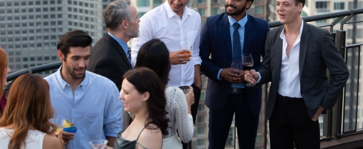 a group of friends stand together talking at a rehearsal dinner