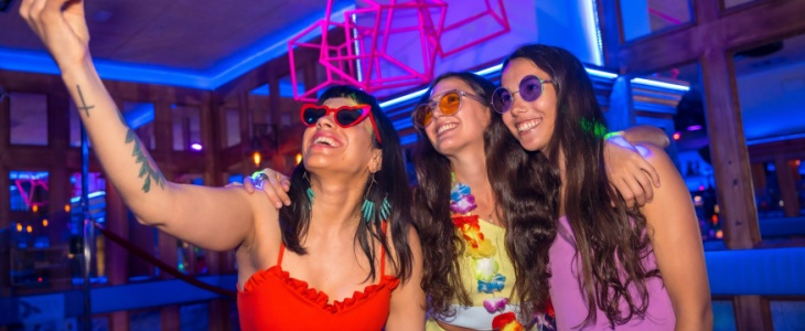 a bride takes a selfie with herself and two friends at a nightclub